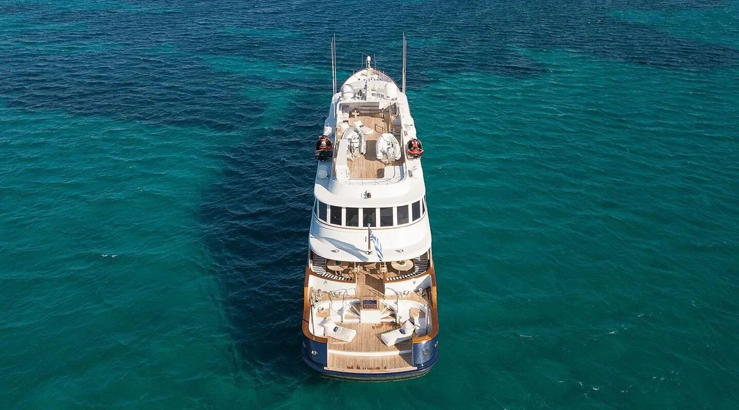 White luxury yacht seen from above with upper deck seating on turquoise sea