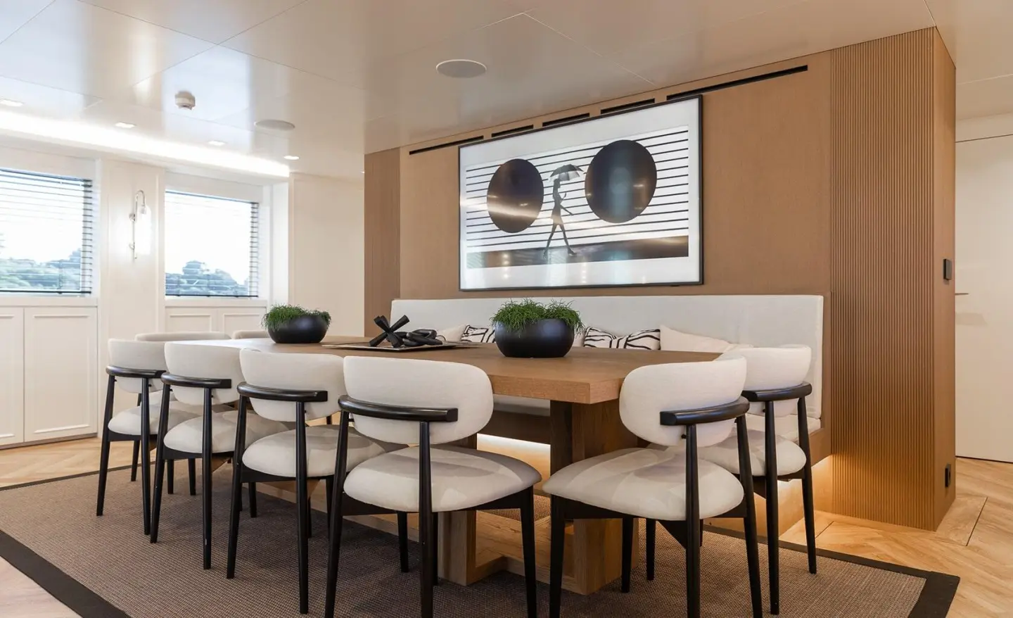 Illusion II yacht dining area with long light wood table and stools