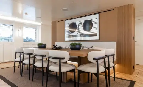 Illusion II yacht dining area with long light wood table and stools