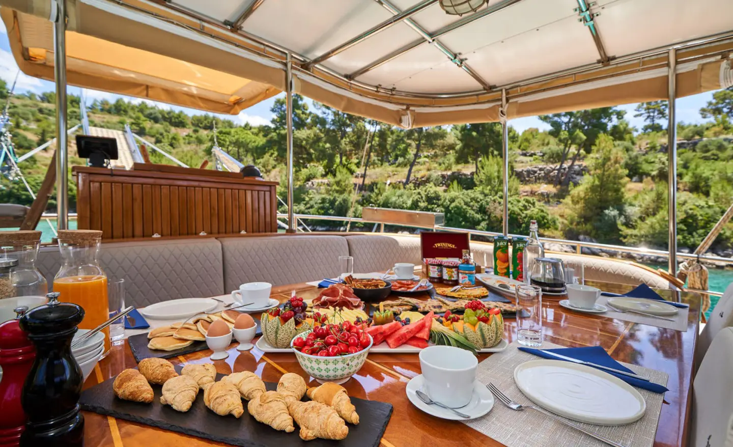 Gulet Libra yacht charter: outdoor dining setup with assorted pastries and fruits on table