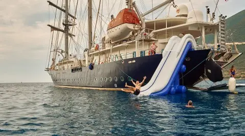 Gulet cruising on waves with a water slide touching the water