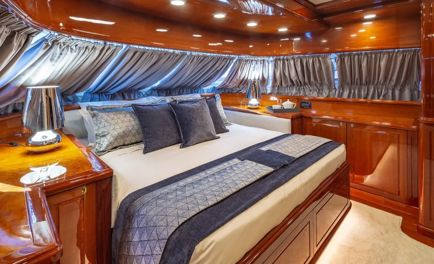 Luxurious yacht cabin with a large bed, blue striped bedding, and wooden accents
