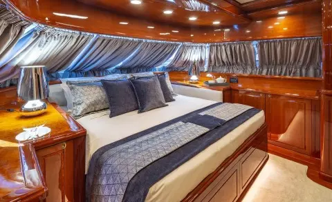 Luxurious yacht cabin with a large bed, blue striped bedding, and wooden accents
