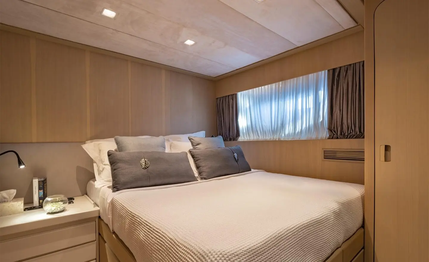 Interior of the yacht with a large bed, two bedside tables and windows