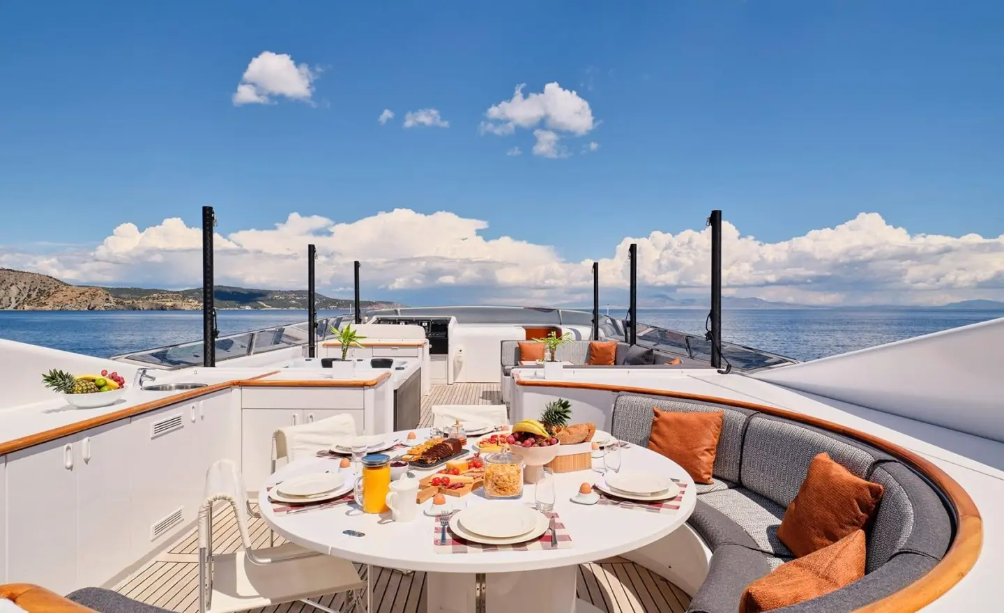 Mobius luxury yacht deck dining area with a round table set for breakfast on a sunny sea