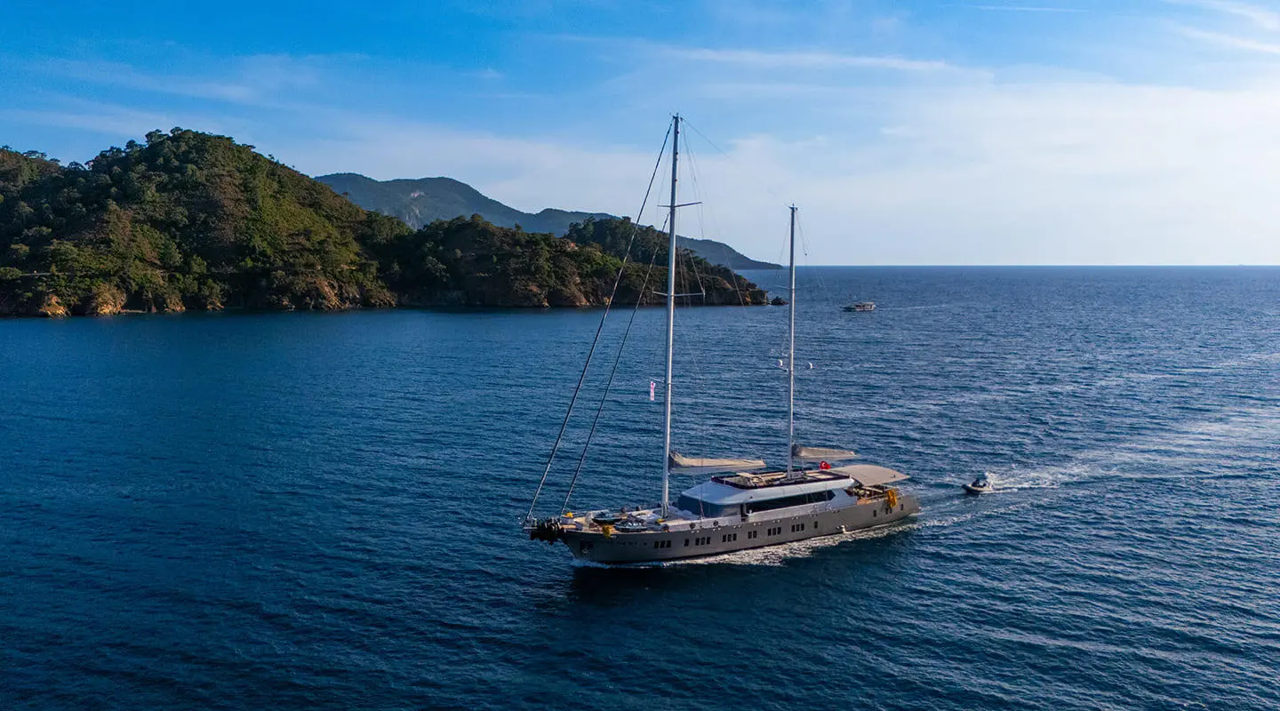 King Of The Sea yacht anchored on calm blue water with coastline in the background