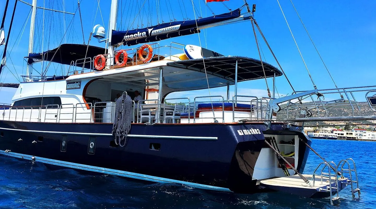 Maske 2 yacht at anchor with blue hull and shaded cockpit on calm water