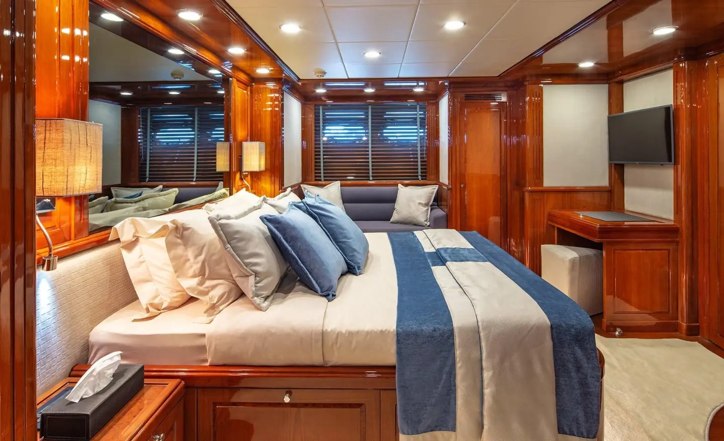 Divine yacht cabin interior with wooden walls, bed, and blue-gray pillows