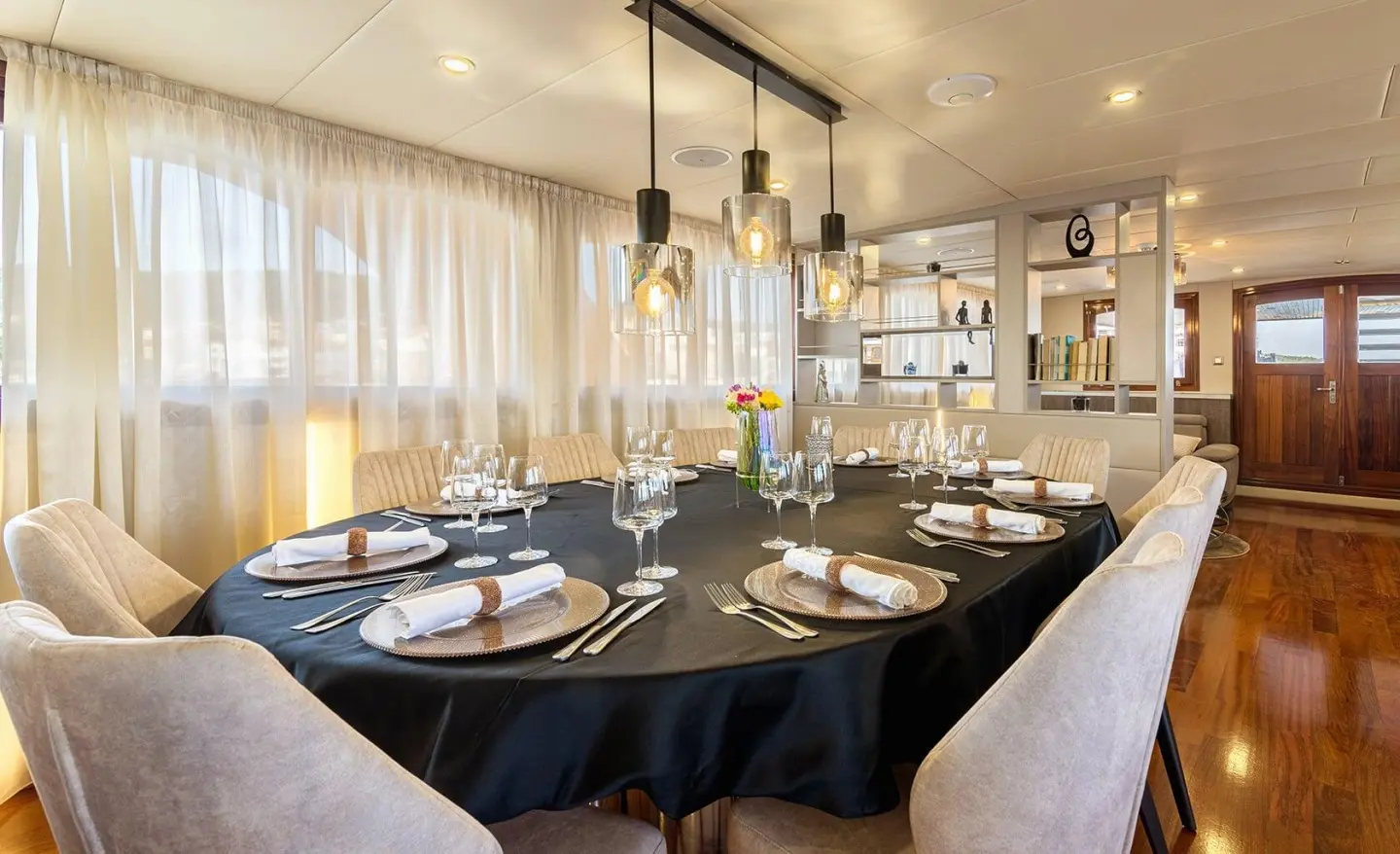 Melody yacht dining table with black tablecloth and cream chairs