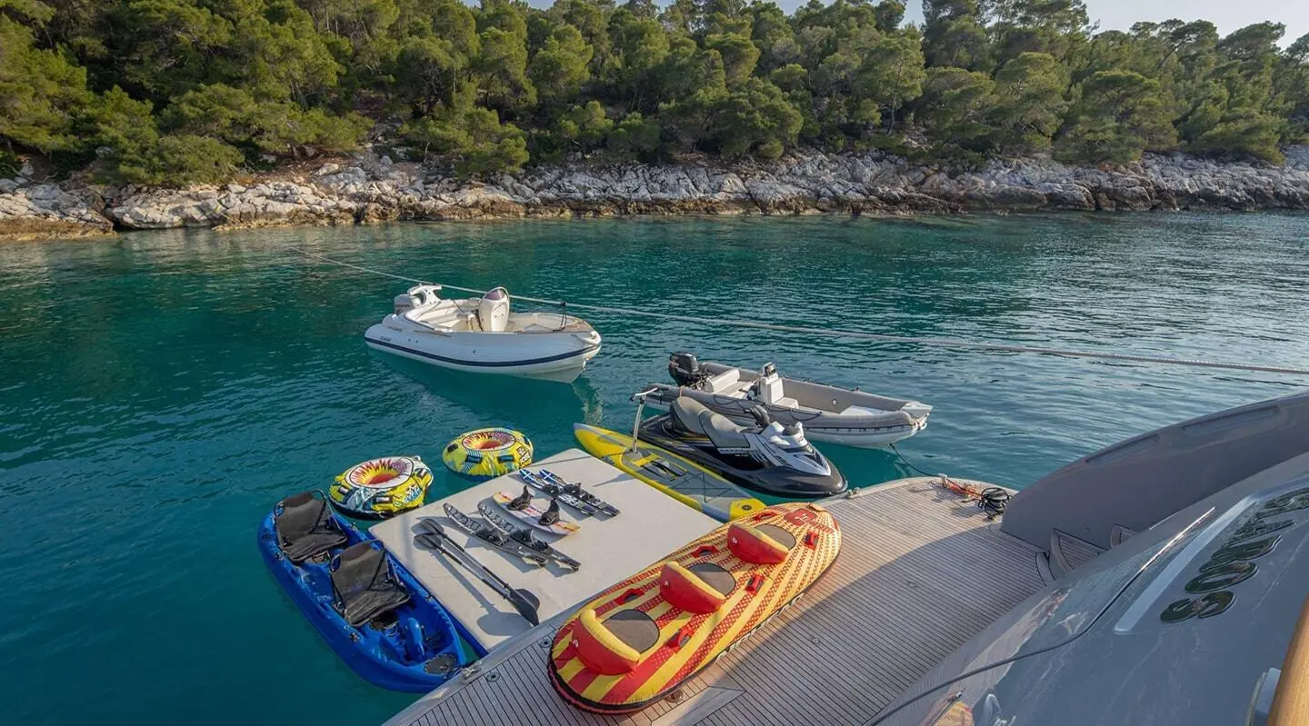 Glaros yacht docked near clear water with small colorful boats nearby