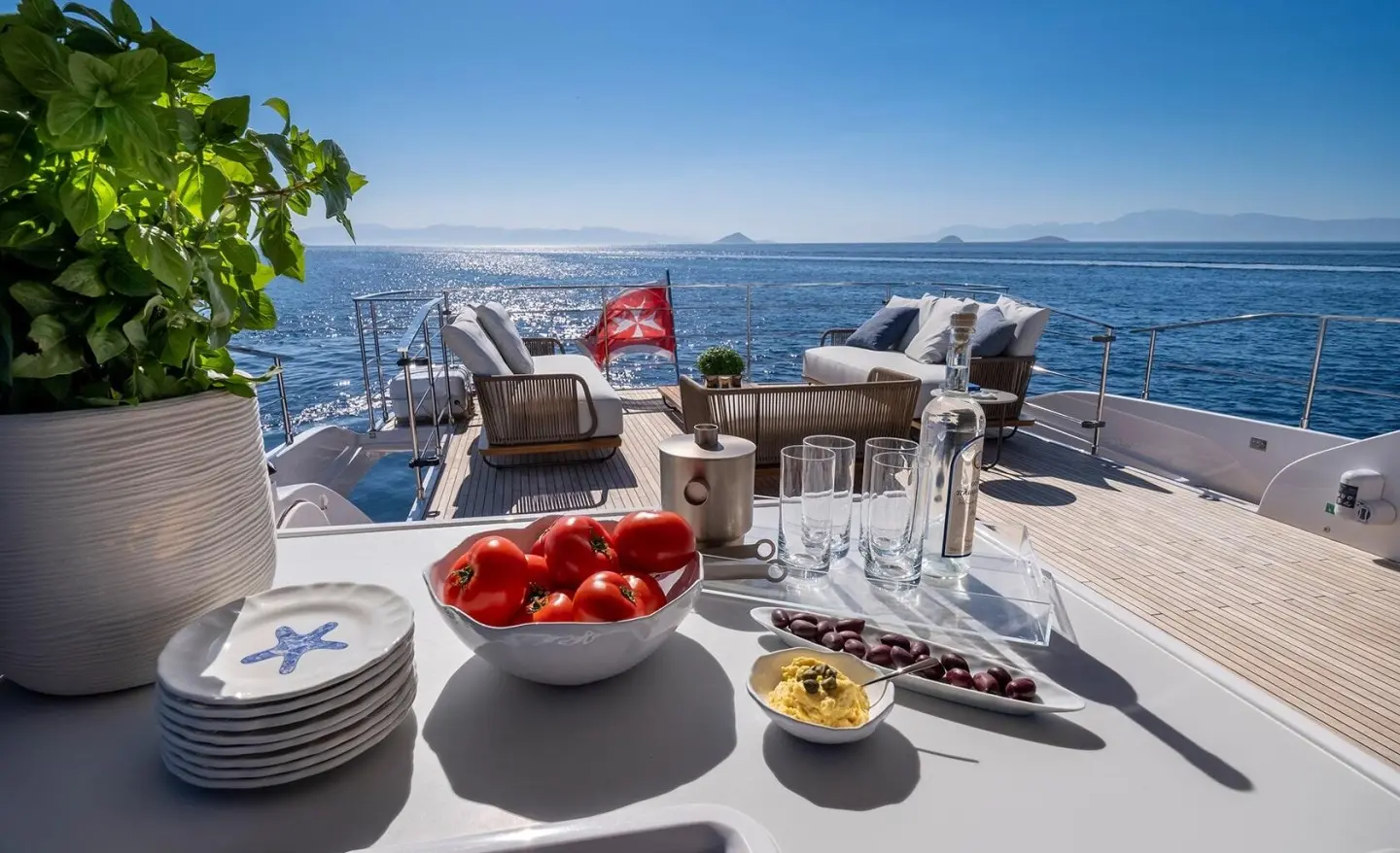 Spica yacht deck at sunset with chairs, table setting, and ocean view