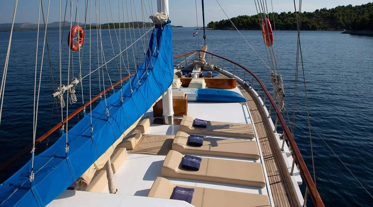 Sunset view from the Malena yacht deck with ropes, sails, and calm sea
