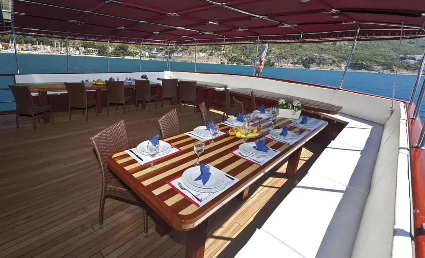 Amorena yacht lounge area with striped table setting on deck under canopy