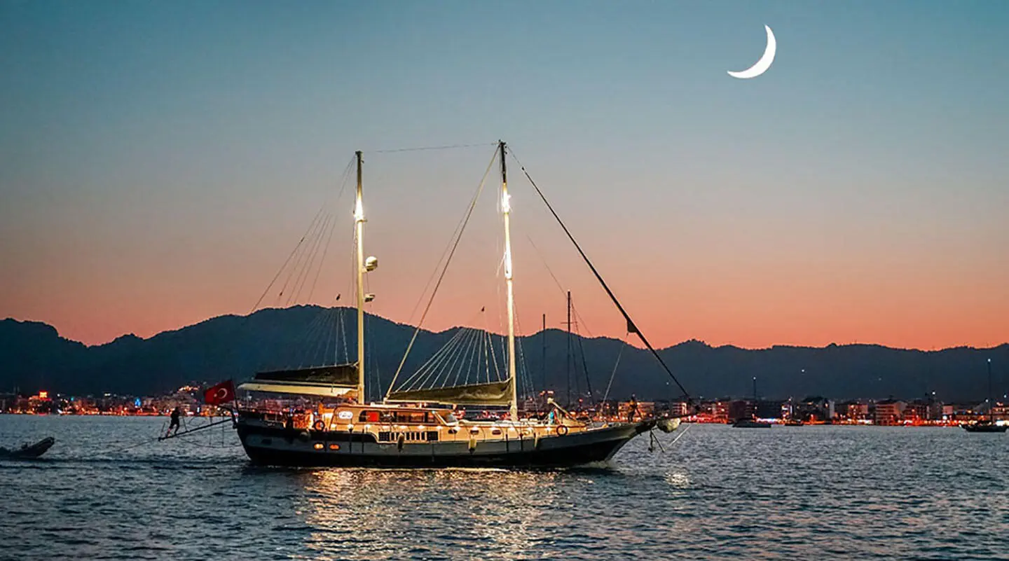 Grand Sailor yacht moored at sunset with calm water and sails raised