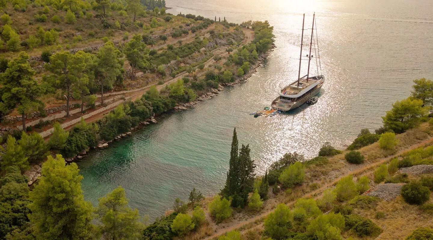 Yacht Anetta docked in a narrow coastal inlet with rocky cliffs