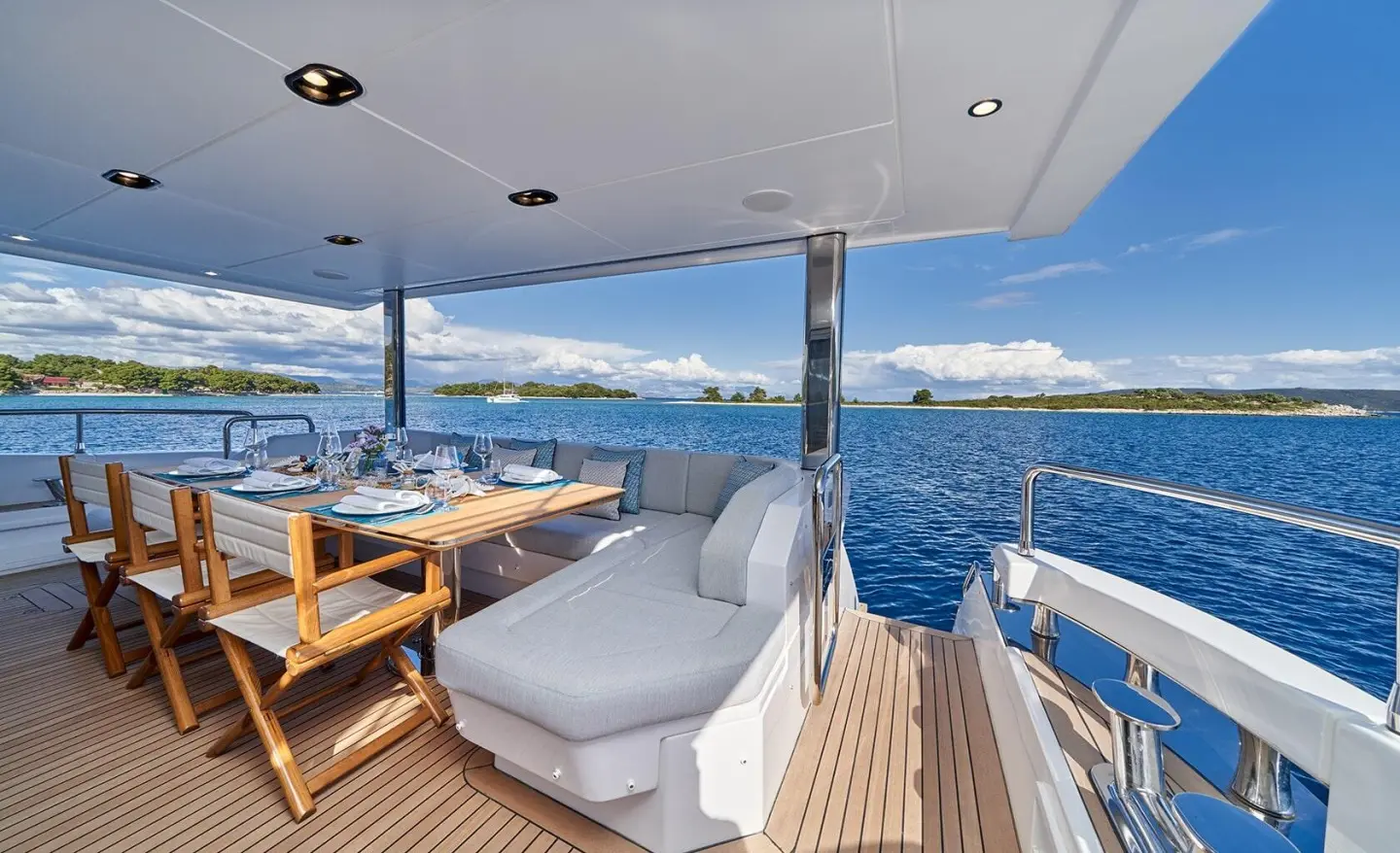 Yacht Aluminia Too exterior dining area with seating, cushions, and blue ocean backdrop