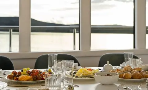 Interior dining area on Maxita yacht with table set for meal and window view