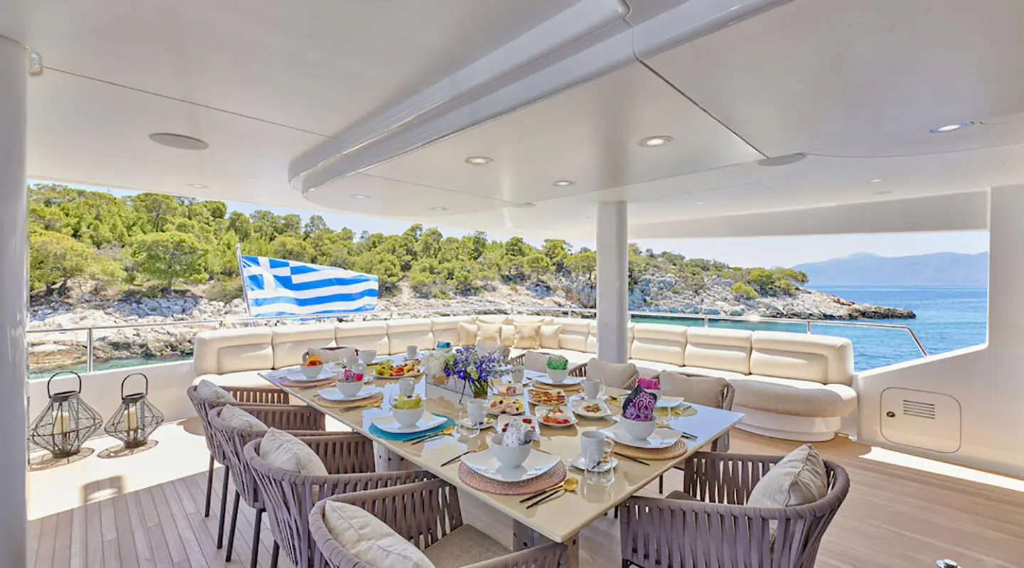 Daloli yacht dining area on deck with table set for sunset meal and ocean view