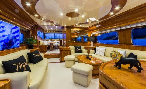 Amoraki luxury yacht interior: salon with cream upholstery, polished wood, seating cushions, and ambient lighting