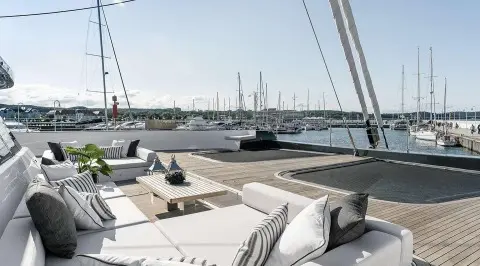 Yacht deck with seating and sails, harbor with moored boats in sunset