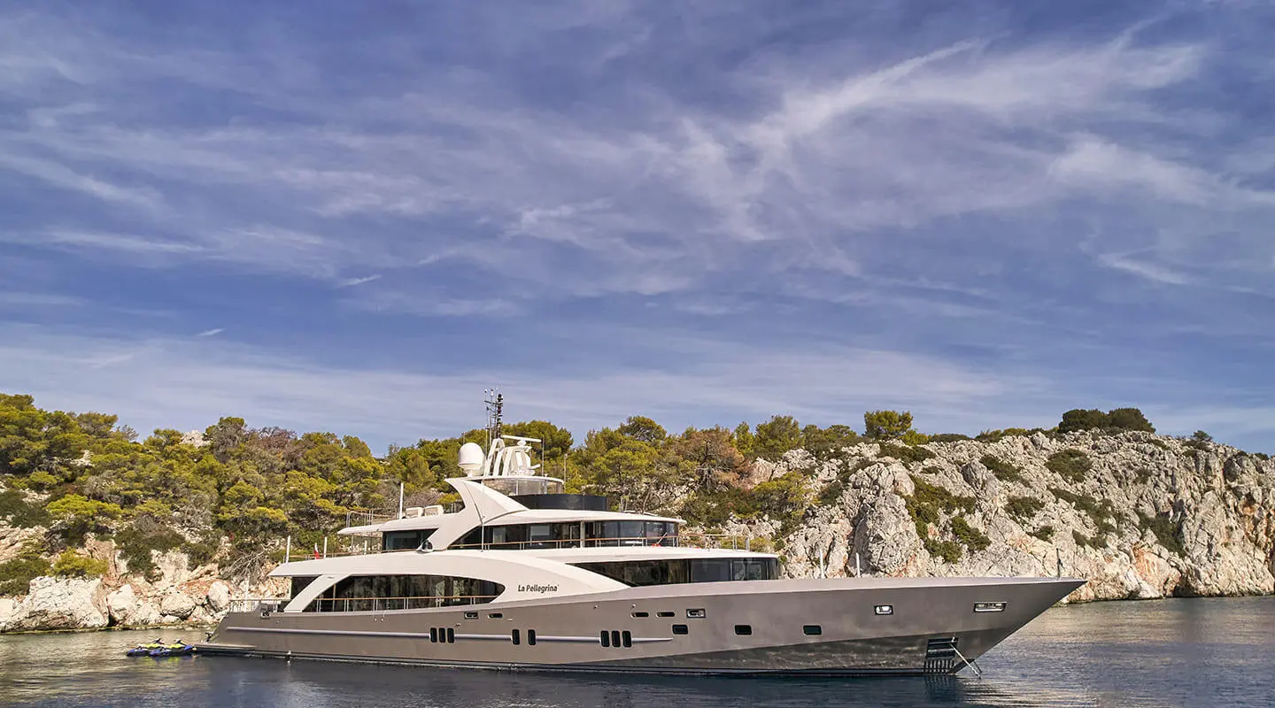 La Pellegrina 1 motor yacht anchored near rocky quay under blue sky