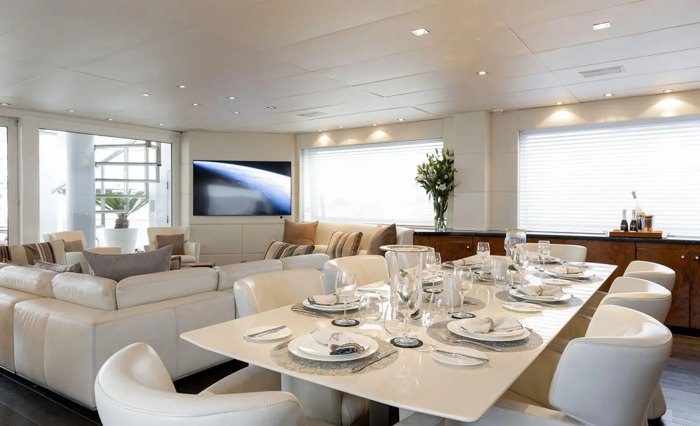 Interior of a yacht salon with a table set for dining and soft lighting