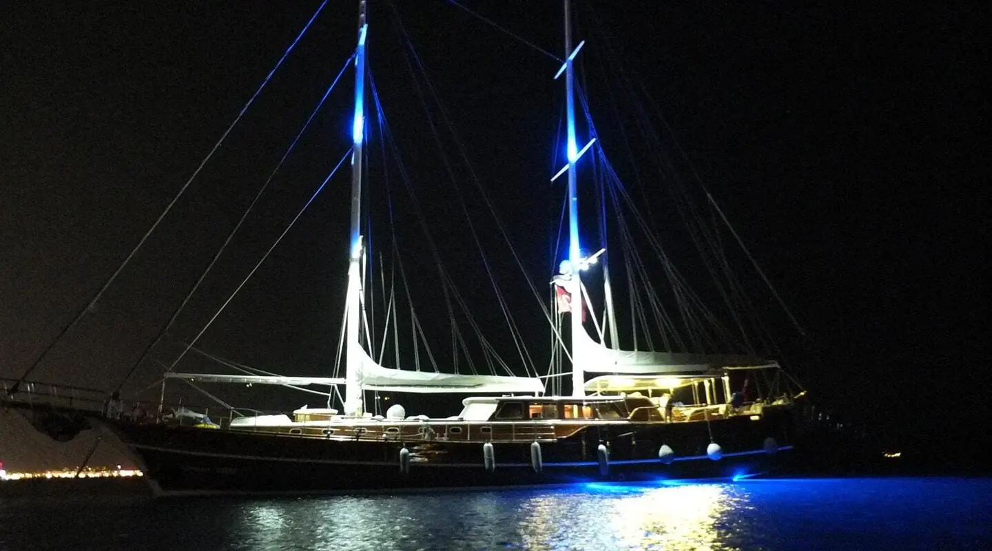 Gulet yacht Kaptan Mehmet Bugra at night, lit masts reflecting on calm water