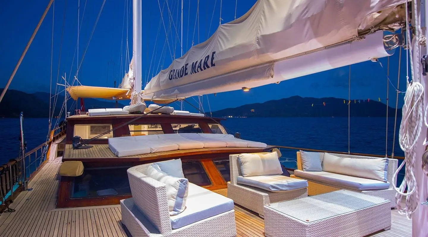 Grande Mare yacht deck seating area with white cushions and blue hull in image