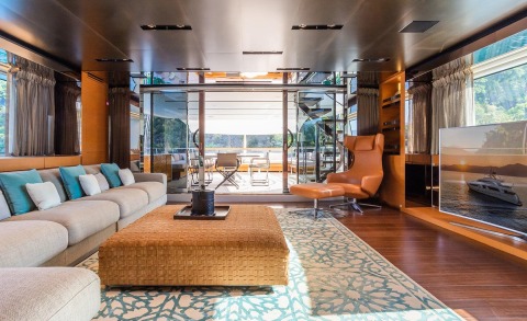 Luxurious yacht interior with a large seating area and coffee table, glass doors opening to outdoors