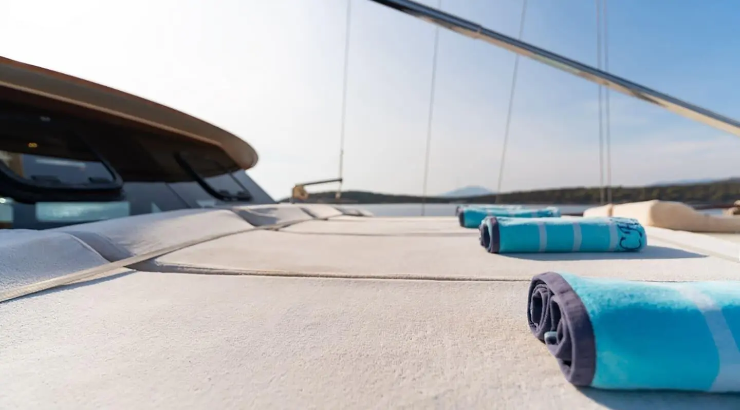 Sunlit deck of Mein Schatz gulet with sun mats and blue life buoy on sand