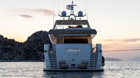 Aquila motor yacht seen from rear, white hulls, multiple decks, calm sea