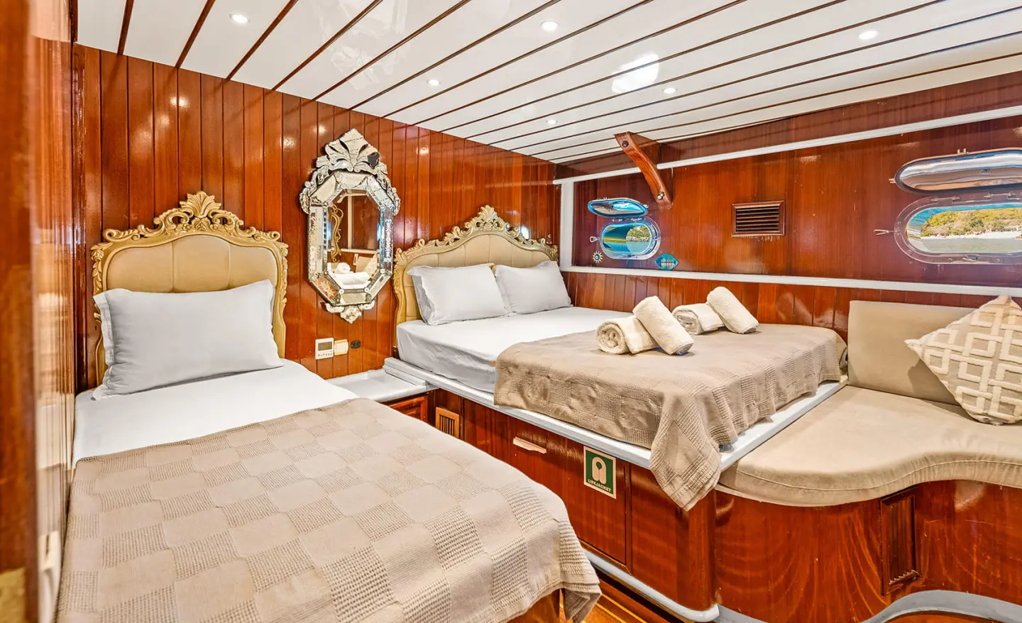Interior of a luxurious yacht with twin beds, wooden panels, and porthole windows