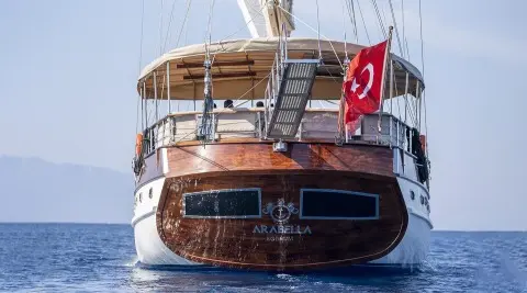 Arabella yacht at sunset with Turkish flag on stern and wooden deck