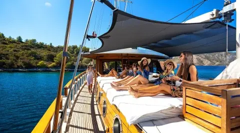 Aborda yacht deck lounging guests sunbathing under a canopy on crystal blue sea