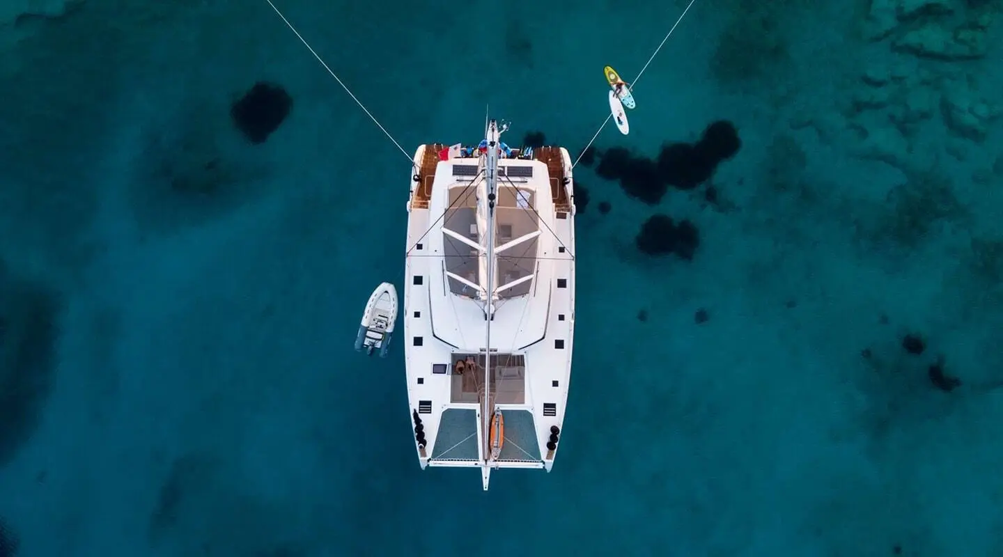 Aerial view of Serenissima yacht anchored in clear turquoise water with small boats nearby