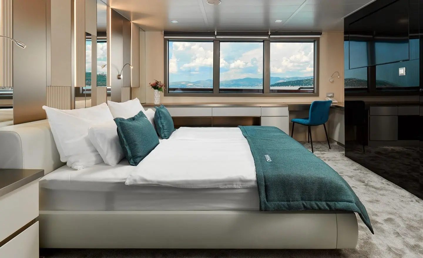 Ohana yacht bedroom with large bed, teal throw, windows view, neutral tones