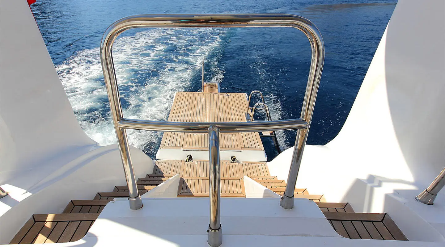 Angelo II yacht deck with metal railings, wooden stairs, and blue sea background