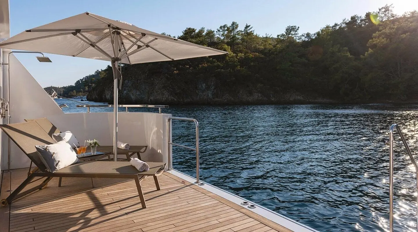 Ocean Breeze deck overlooking calm blue water at sunset, sunlit railing