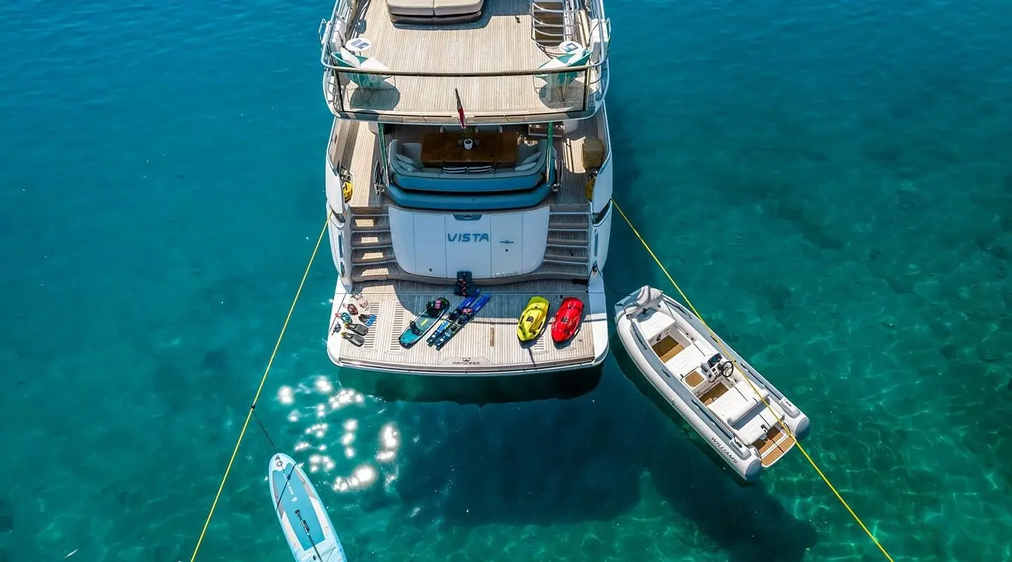 View of Vista motor yacht anchored with a small tender nearby in clear blue water