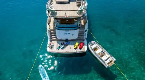 View of Vista motor yacht anchored with a small tender nearby in clear blue water