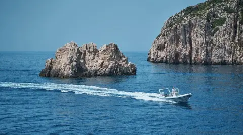 La Perla yacht anchored in blue sea with rock formations nearby