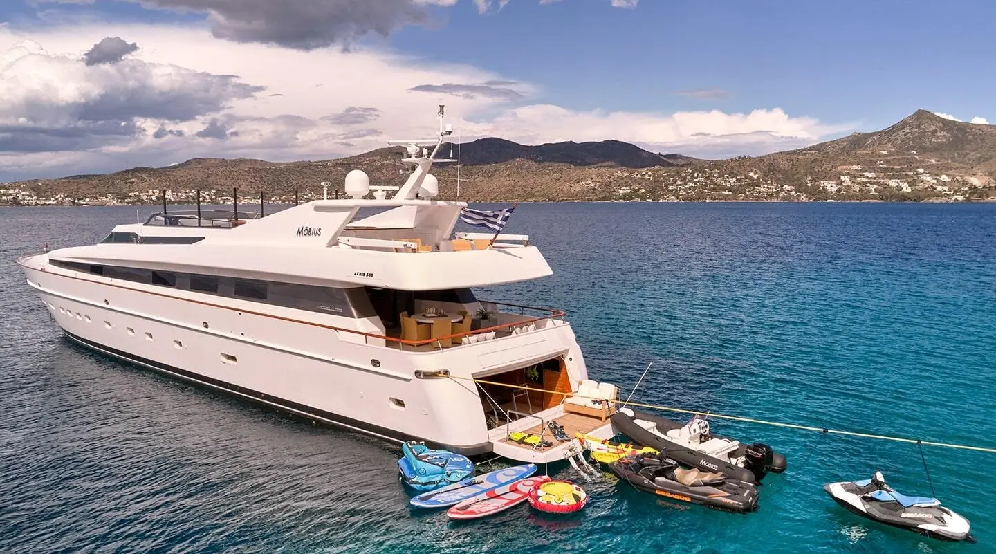 Luxurious white Mobius yacht anchored near rocky coastline at sunset
