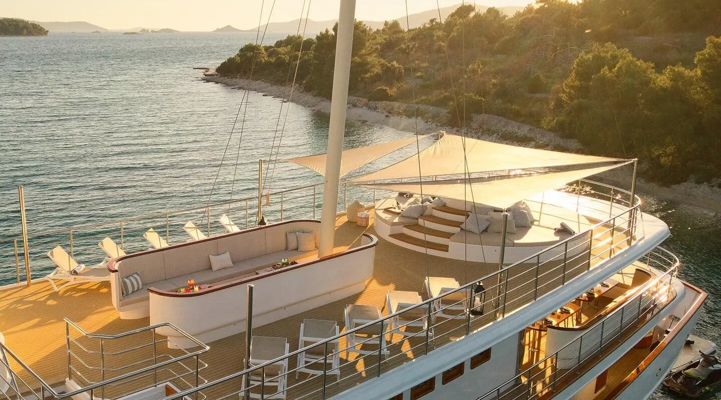 Sunlit yacht deck with lounge seating and shaded area on upper deck
