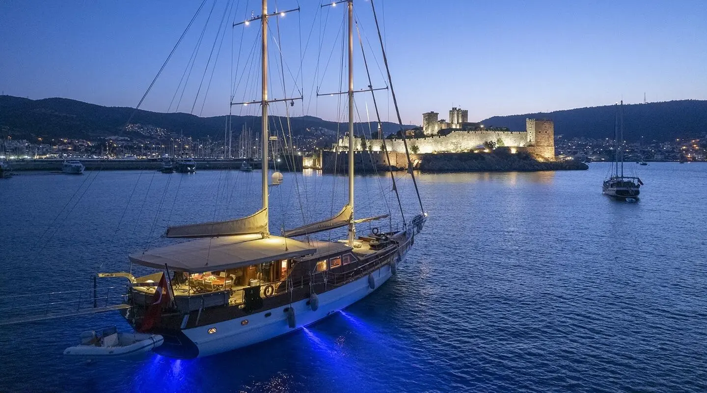Arabella gulet yacht anchored near a coastal town at sunset