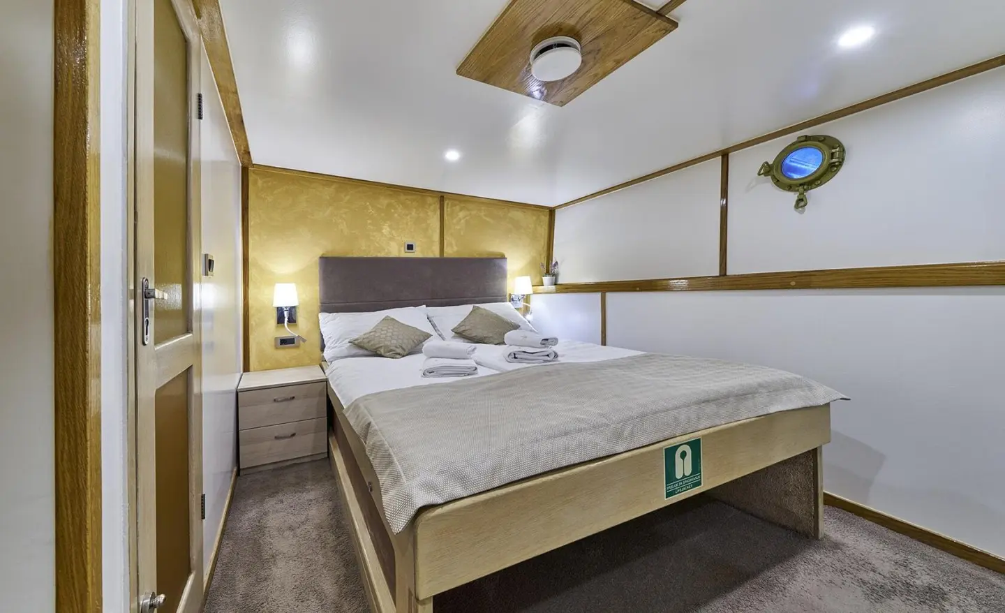 Romanca yacht interior with a double bed, wooden accents, and ceiling fan