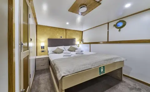 Romanca yacht interior with a double bed, wooden accents, and ceiling fan