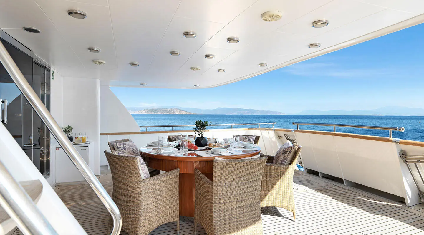 Idylle yacht on sunset dining deck with wicker chairs and ocean view