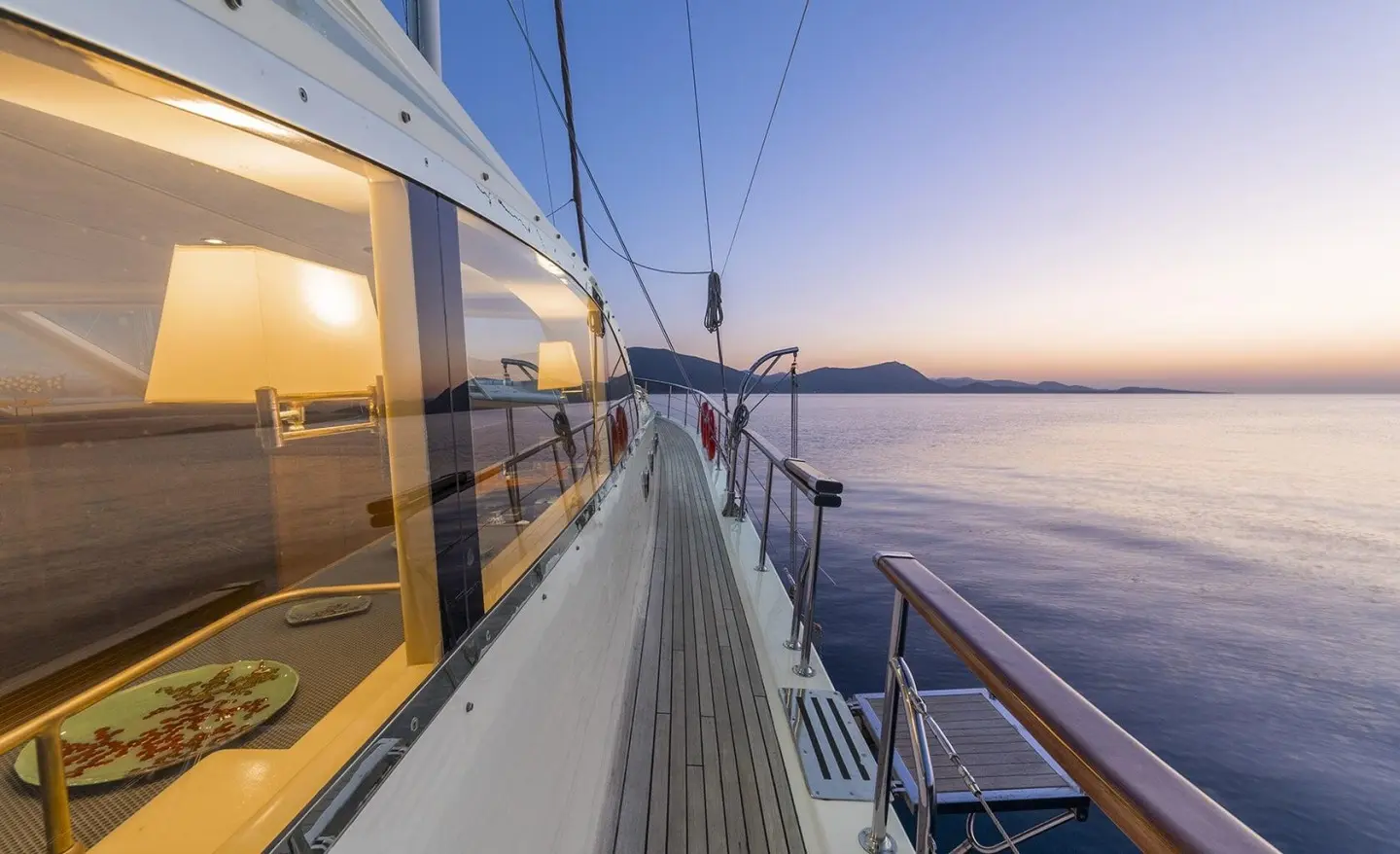 Sunset over calm sea seen from the Queen Of Sea yacht deck with railing