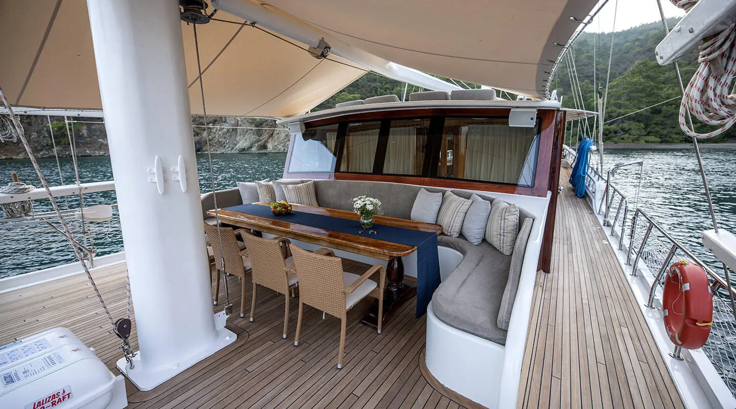 Kayhan 5 gulet lounge area with wooden deck and dining table set under a canopy
