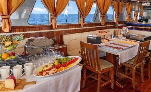 Gulet Cesarica saloon with wooden table and chairs, sea view through windows